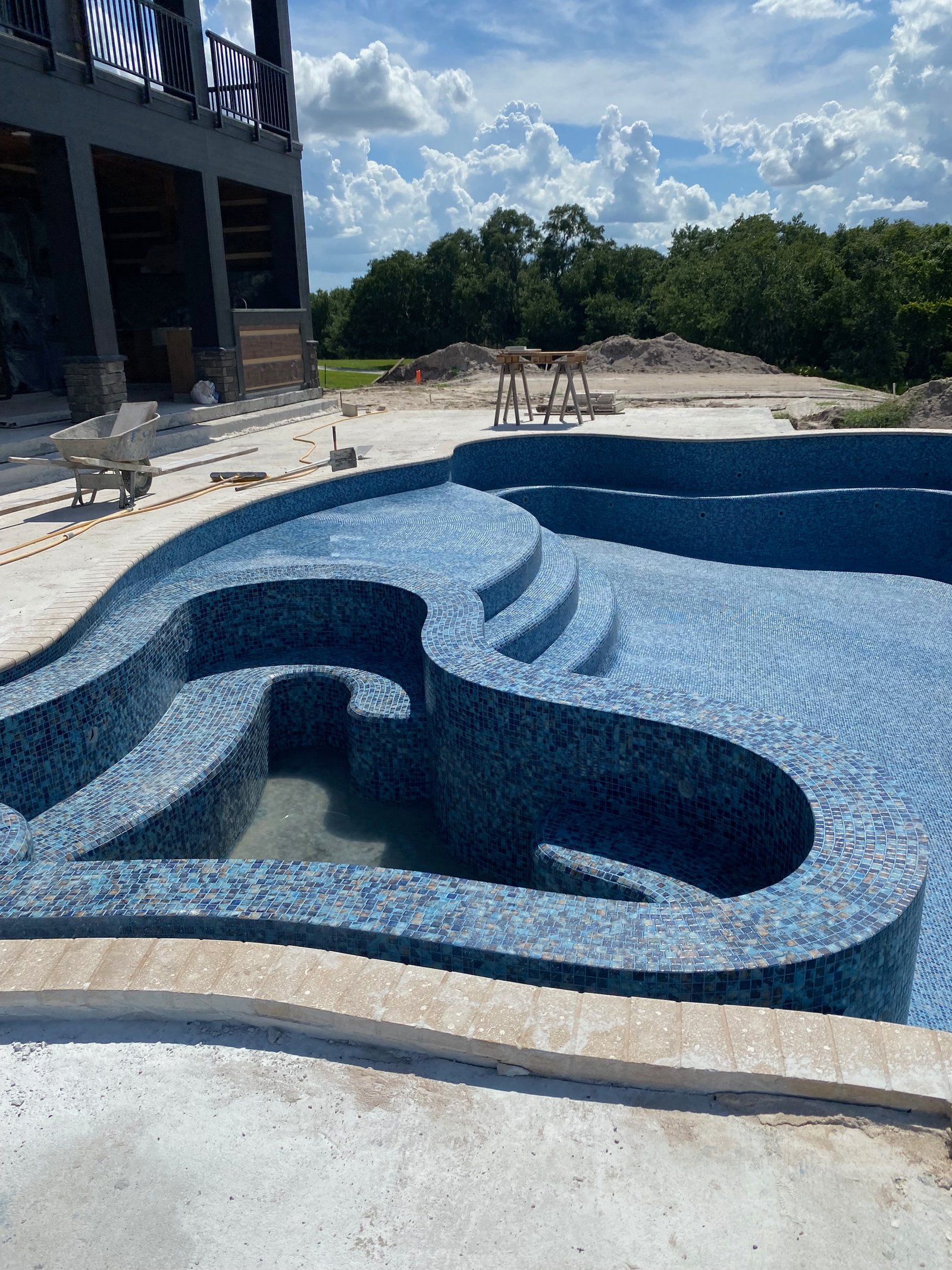 Full pool tile installation with custom curved tanning ledge